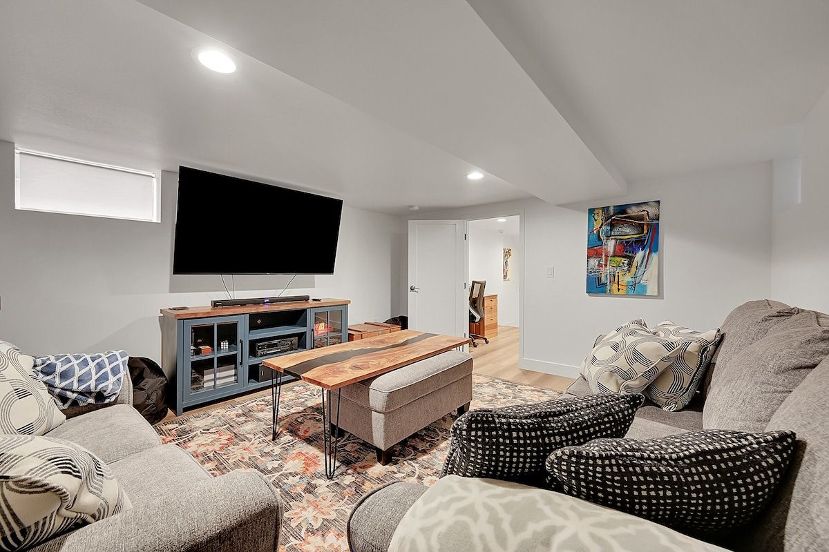 Family room with a wall-mounted TV, a sectional and floor cushions