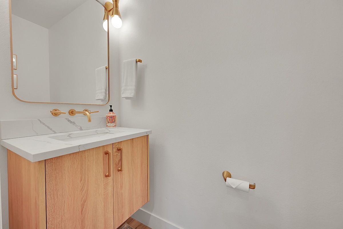 Powder room with brass fixtures and a round mirror