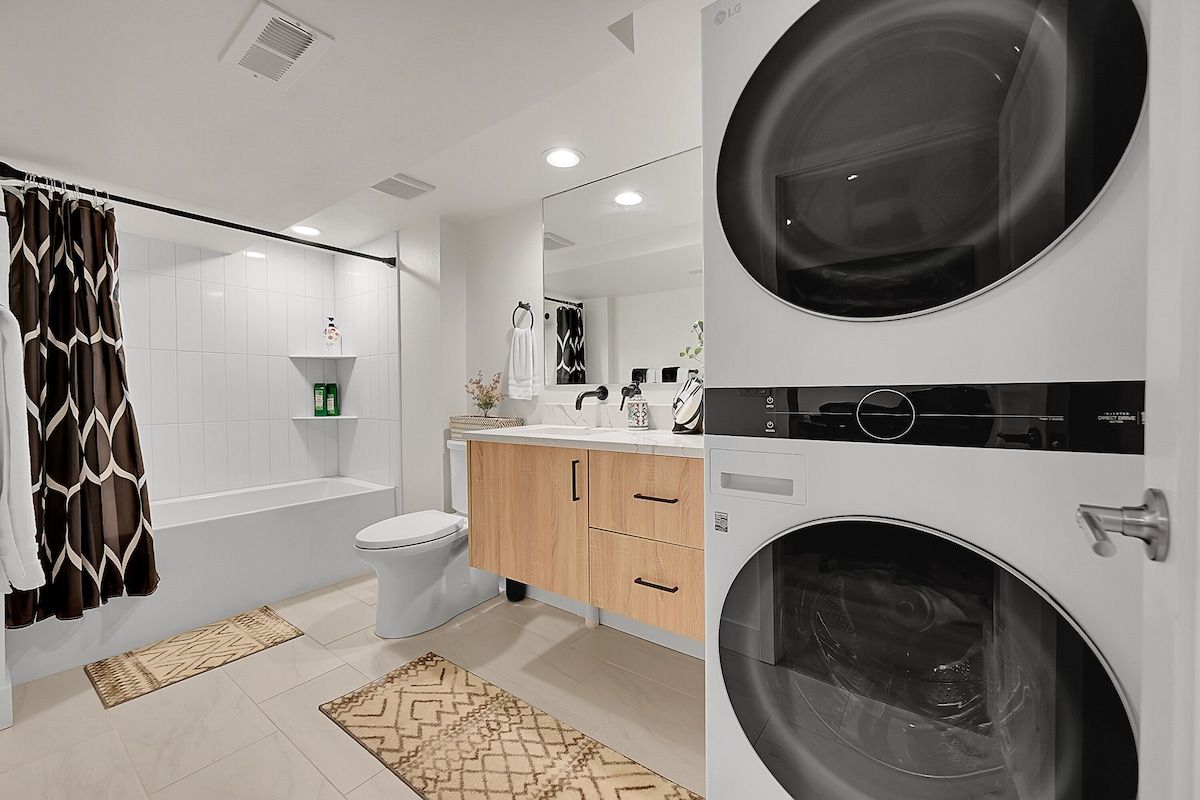 Bathroom with a tub and a stacked washer and dryer
